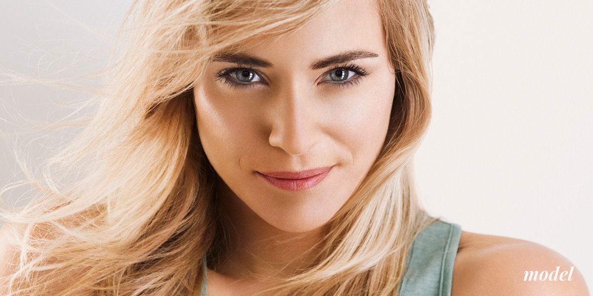 Close-up of a smiling model with blonde hair.
