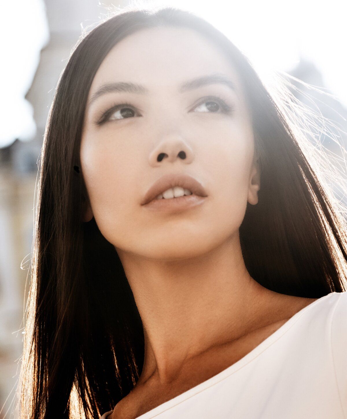 Young woman looking up against sunlight backdrop.