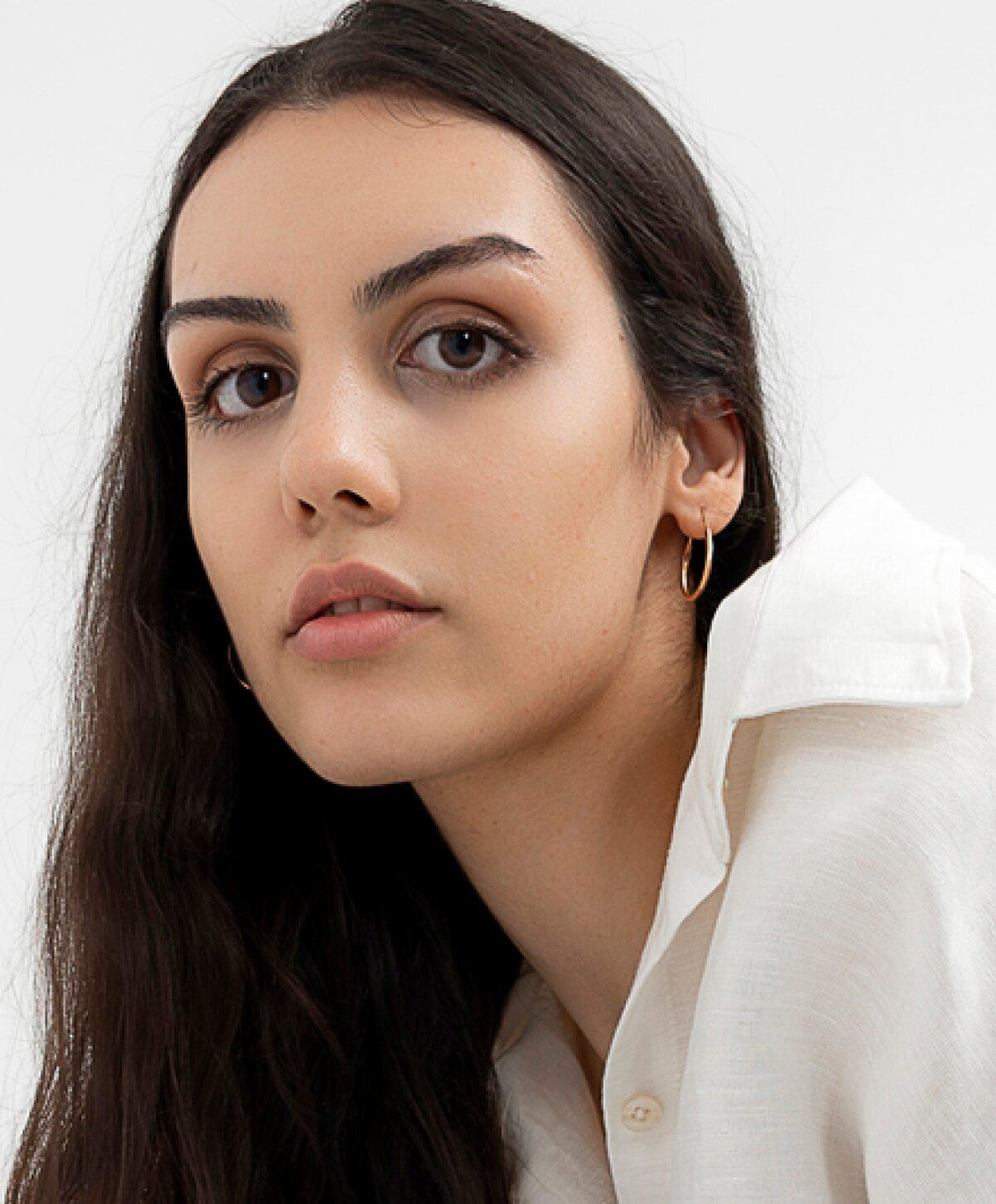 Model with long hair and hoop earrings.