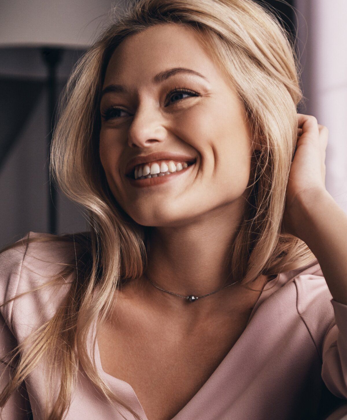 Smiling woman with blonde hair and jewelry.