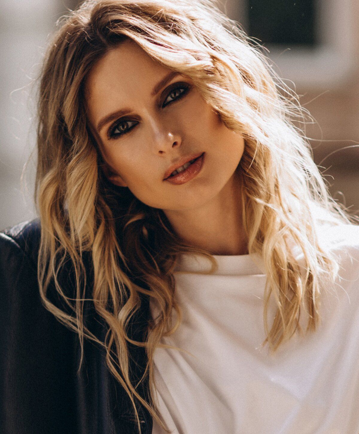 Smiling woman with wavy hair outdoors.