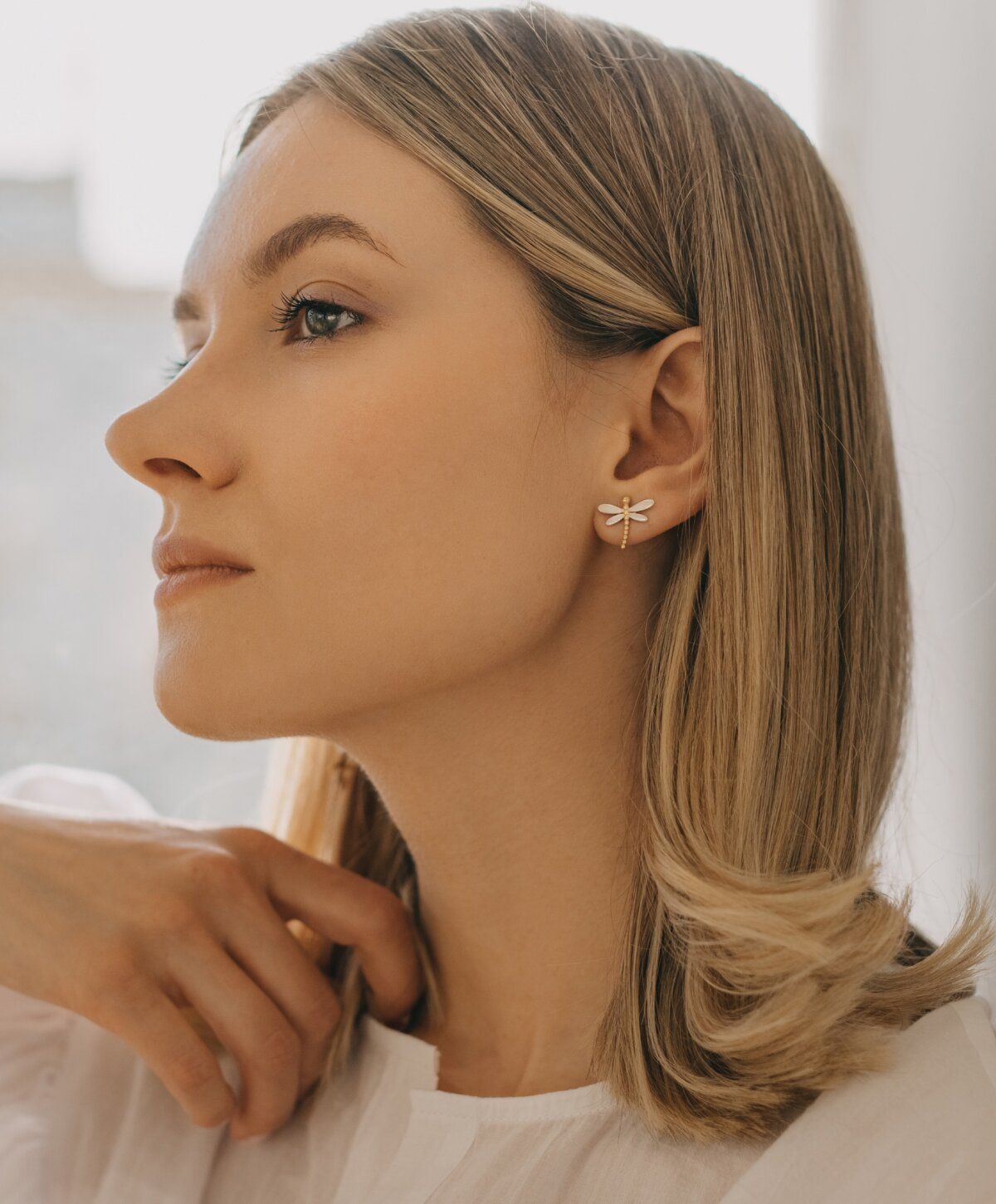 Profile of a woman with dragonfly earrings.