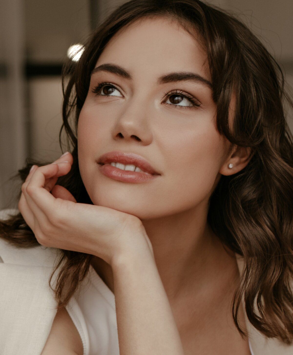 Woman with thoughtful expression and soft makeup.
