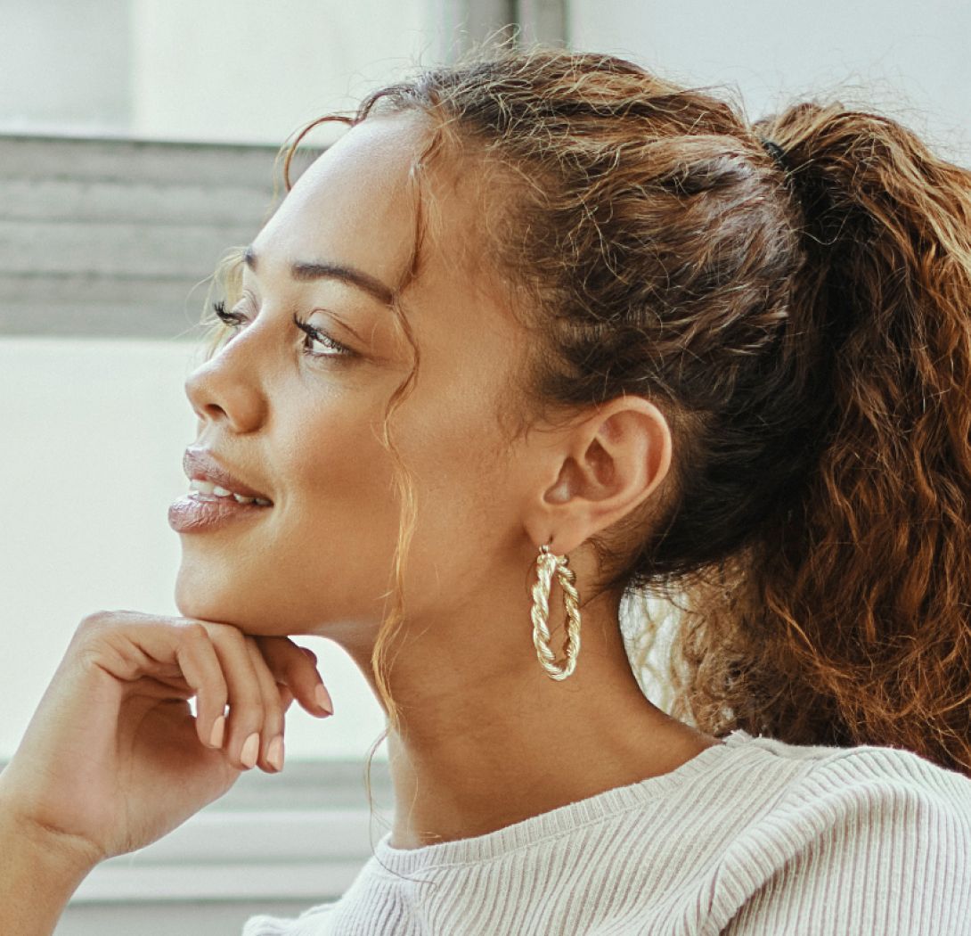 Woman with curly hair wearing hoop earrings.