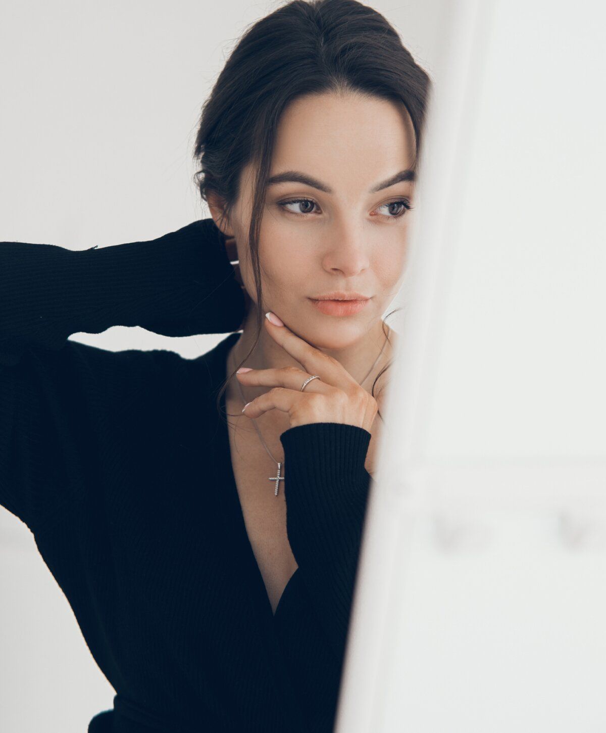 Woman in black sweater touching her neck.