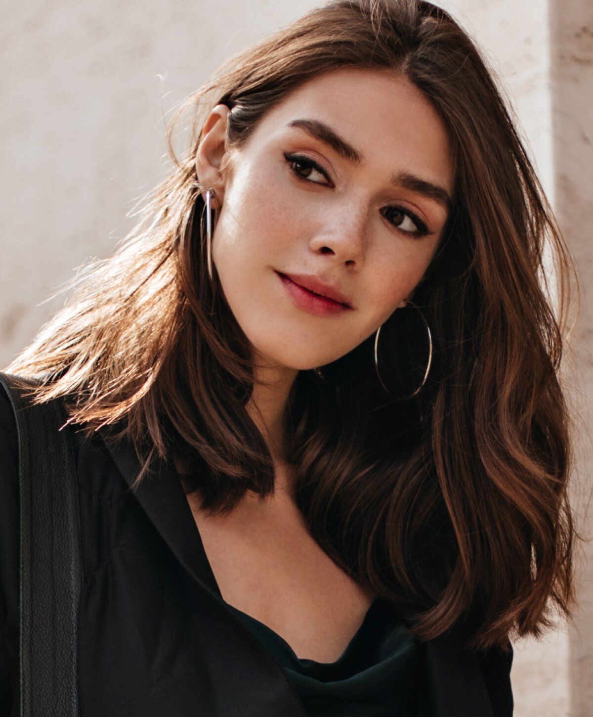 Young woman with long hair and hoop earrings.