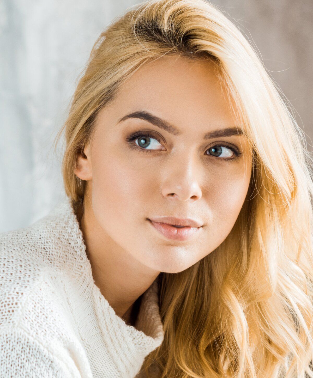 Smiling woman with blonde hair in soft lighting.