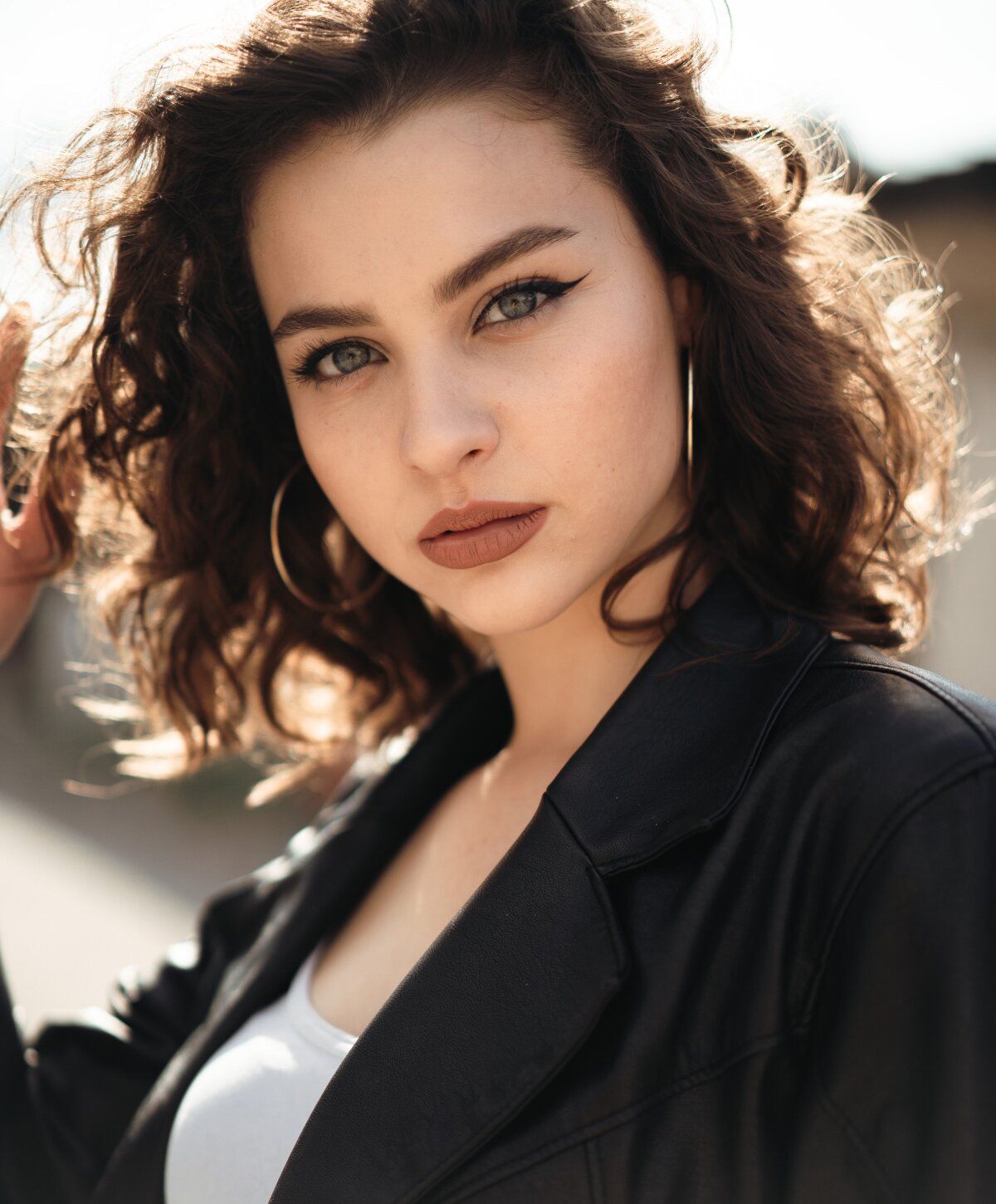 Young woman with curly hair and hoop earrings.
