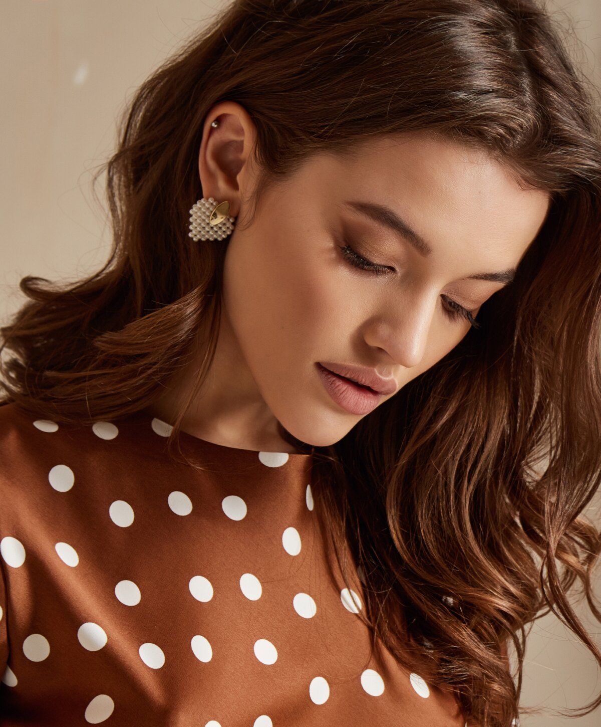 Woman with brown polka dot dress and earrings.