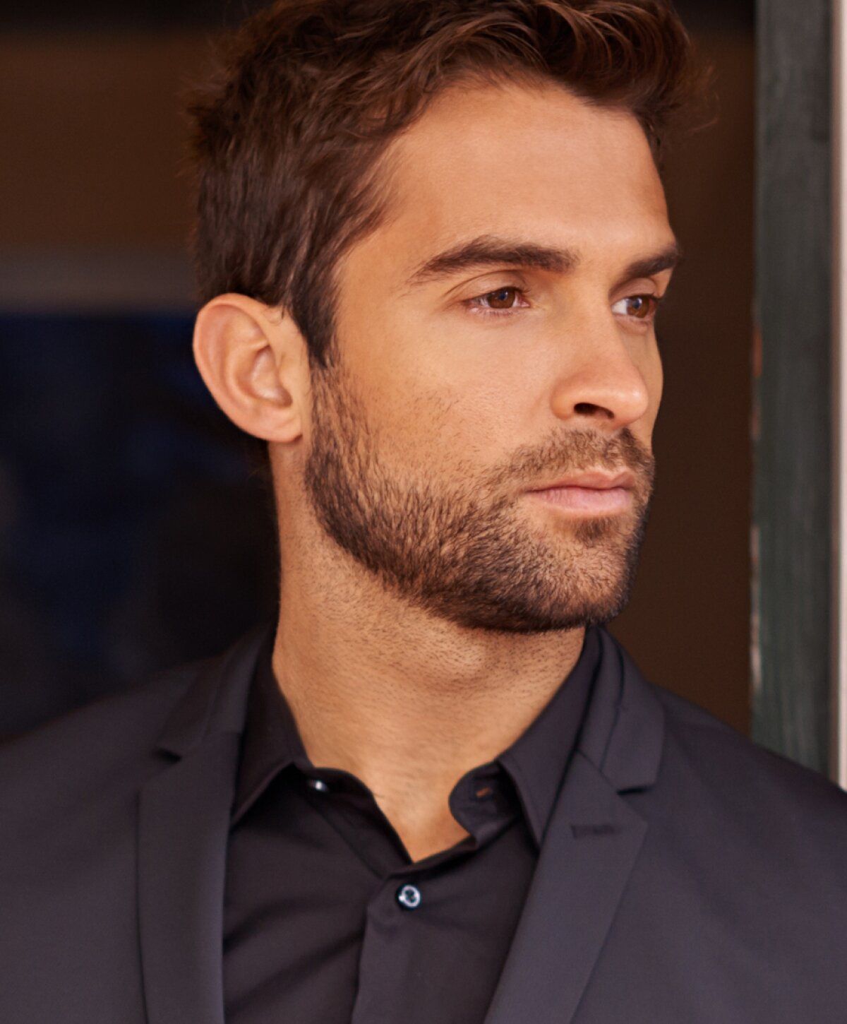 Man with beard wearing black suit jacket.
