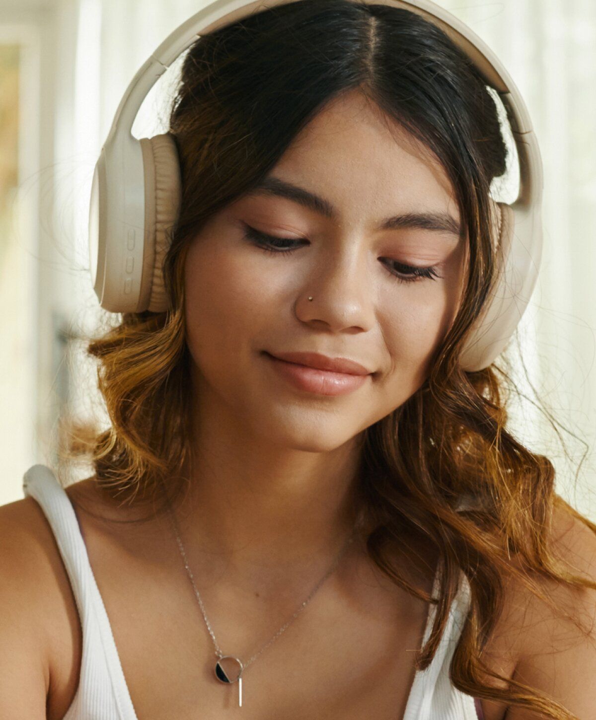 Young woman wearing headphones, smiling softly.