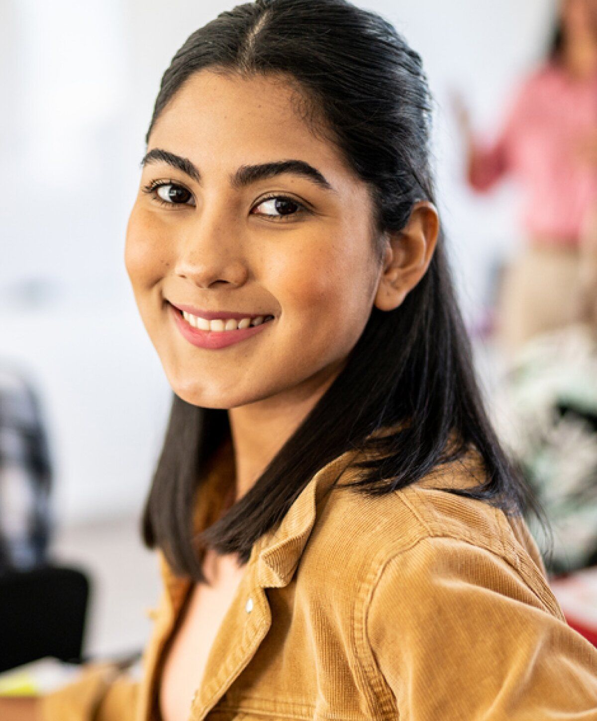 Smiling woman in casual setting, looking at camera.